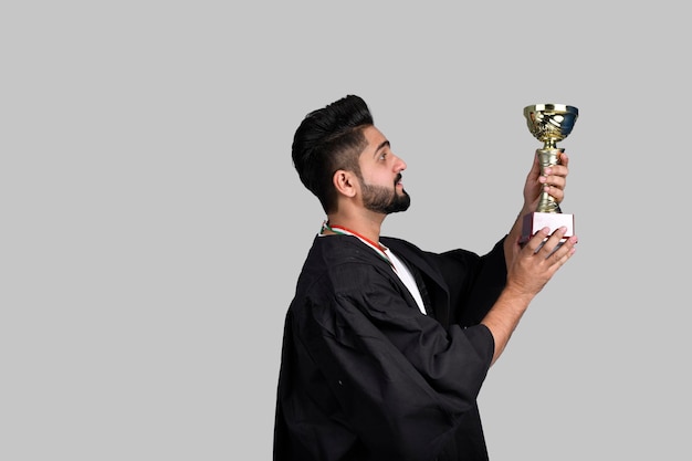 Heureux étudiant diplômé tenant un trophée d'or modèle pakistanais indien