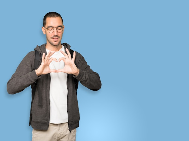 Heureux étudiant faisant un geste d'amour avec ses mains