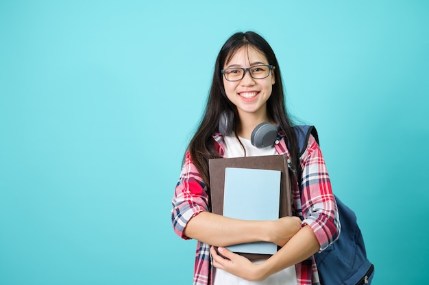 Heureux étudiant. Joyeuse fille asiatique souriante à la caméra debout avec sac à dos en studio sur fond bleu. Retour au concept de l'école.