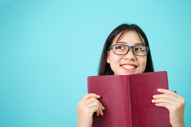 Heureux étudiant. Joyeuse fille asiatique souriante à la caméra debout avec sac à dos en studio sur fond bleu. Retour au concept de l'école.