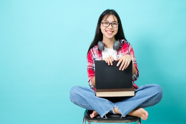 Heureux étudiant. Joyeuse fille asiatique souriante à la caméra debout avec sac à dos en studio sur fond bleu. Retour au concept de l'école.