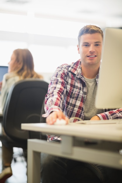 Photo heureux étudiant regardant la caméra dans la salle informatique