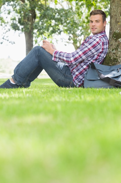 Photo heureux étudiant utilisant sa tablette pour étudier à l'extérieur