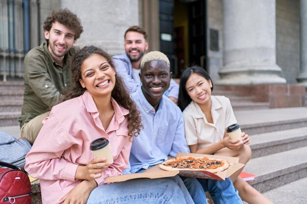 Photo heureux étudiants s'amusant tout en partageant et en mangeant de la pizza