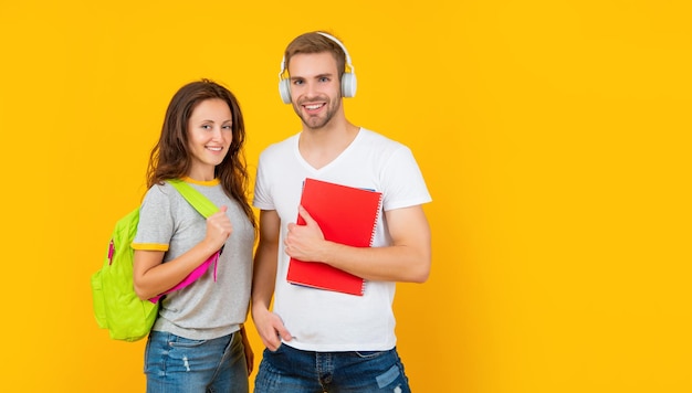 Heureux étudiants universitaires dans des écouteurs avec classeur et sac à dos avec copie espace éducation