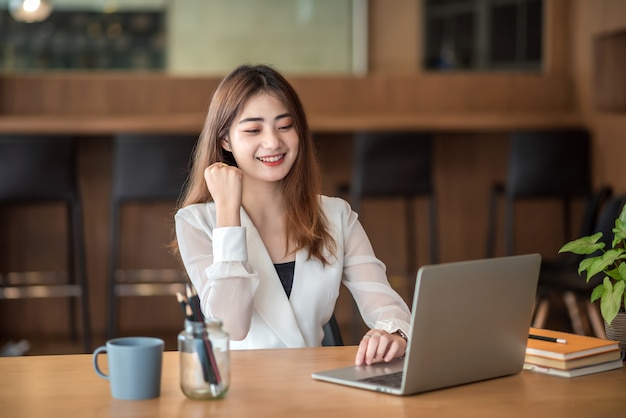 Heureux excité jeune femme d'affaires asiatique réussie travaillant au bureau.