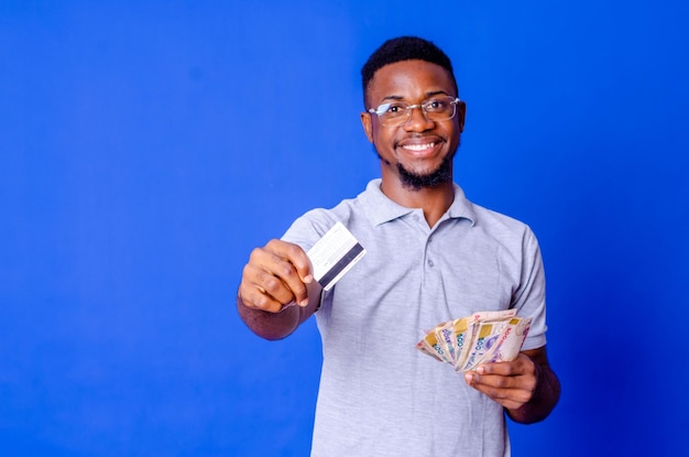 Heureux et excité jeune homme africain tenant des liasses d'argent et de carte