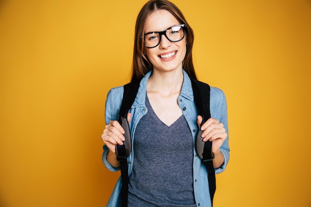 Heureux et excité mignon jeune étudiant fille portrait dans des verres avec sac à dos isolé en studio