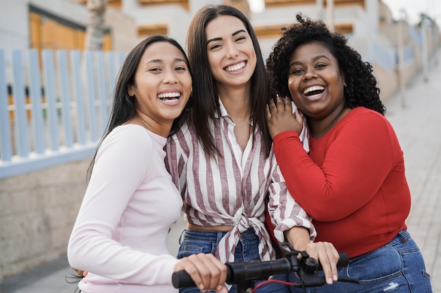 Heureux les filles latines s'amusant avec un scooter électrique en plein air en ville - L'accent principal sur le visage de la femme au centre