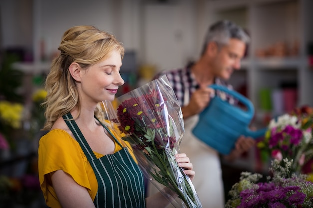 Heureux fleuriste femelle sentant un bouquet de fleurs