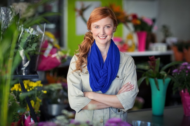 Heureux fleuriste femme debout avec les bras croisés dans un magasin de fleurs