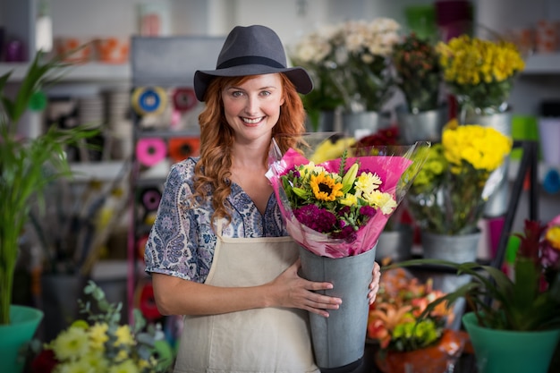 Heureux fleuriste femme tenant un vase à fleurs