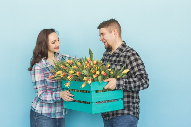 Heureux fleuristes fixant des tulipes dans une grande boîte en bois