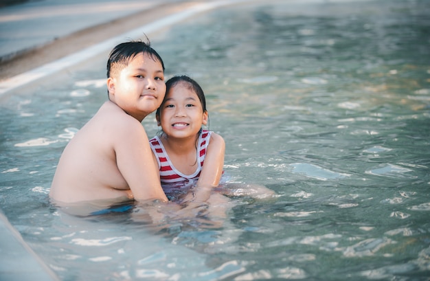 Heureux frère et sœur jouant dans la piscine