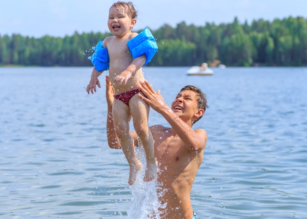 Heureux frère et soeur à la mer s'amuser et éclabousser de l'eau en été