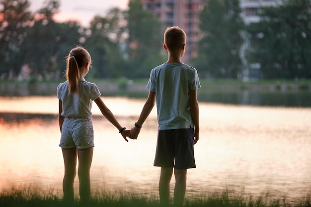 Heureux frères et sœurs debout ensemble main dans la main dans le parc d'été