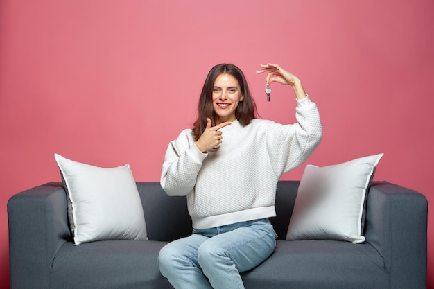 Heureux gagnant locataire locataire d'un nouvel appartement à la maison fier propriétaire montrant les clés d'un appartement moderne assis