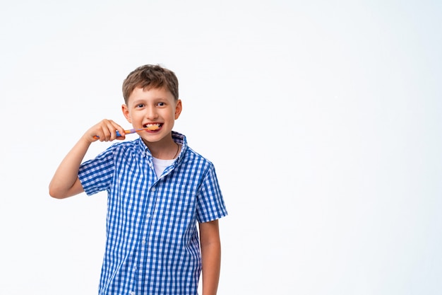 Heureux garçon de 7 ans, souriant, se brossant les dents