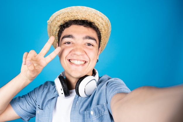 Heureux garçon adolescent hispanique faisant signe de paix avec la main tout en prenant un selfie