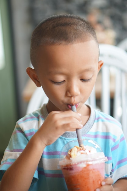 Heureux garçon appréciant les smoothies aux fruits frais