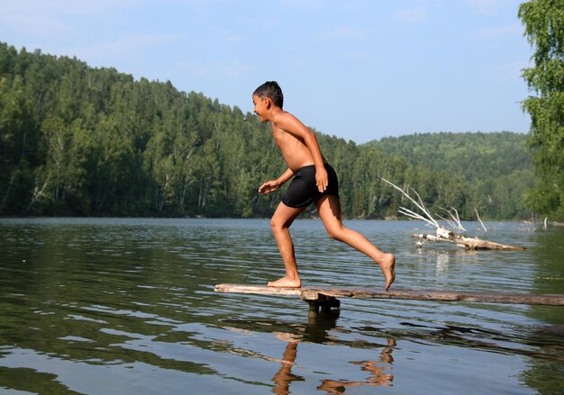 Heureux garçon asiatique plongeant dans le lac