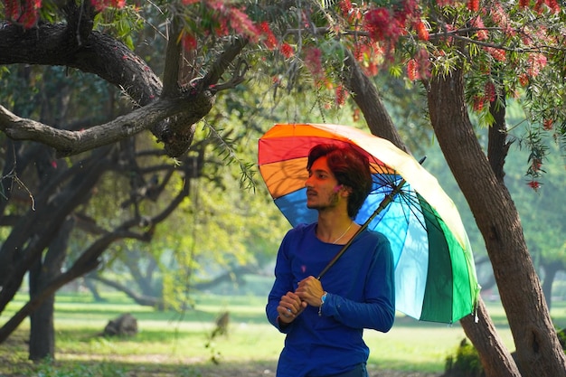 Heureux garçon asiatique tenant un parapluie coloré en été en plein air
