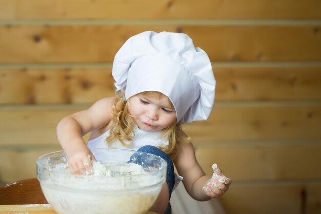 Heureux garçon enfant cuisinier pétrir la pâte