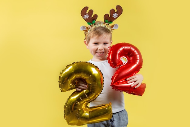 Heureux garçon enfant drôle en costume de renne de Noël rouge avec des numéros de ballon