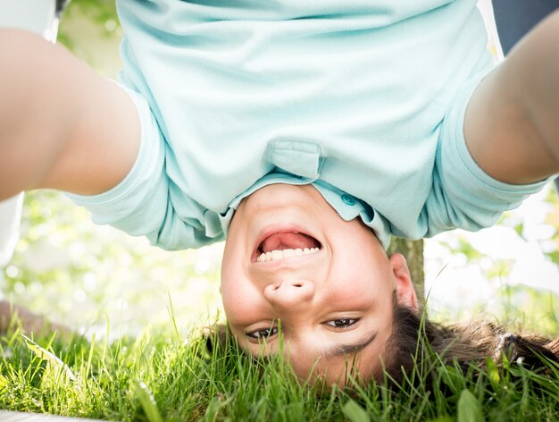 Photo heureux garçon à l'envers dans l'herbe