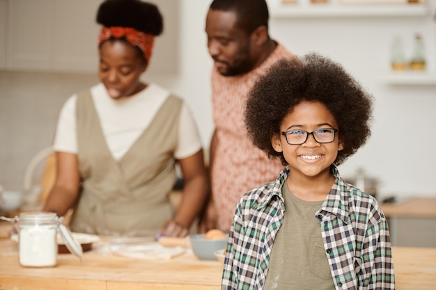 Heureux garçon à lunettes souriant contre la cuisine de ses parents