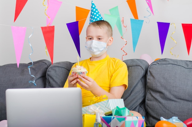 Heureux garçon en masque facial médecine célèbre son anniversaire par appel vidéo sur ordinateur portable