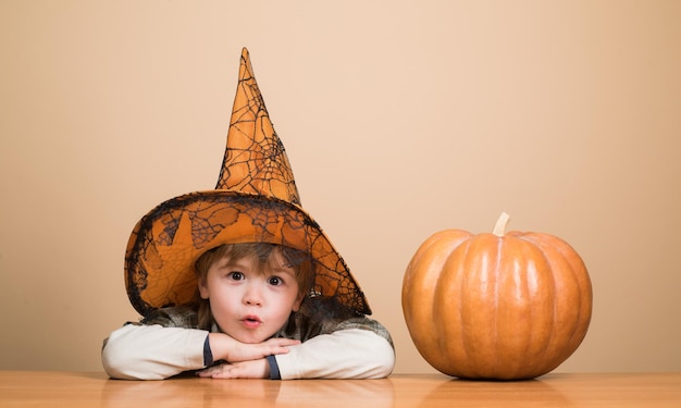 Heureux garçon mignon d'halloween au chapeau de sorcière avec citrouille d'halloween jack o lantern boy habillé en truc ou