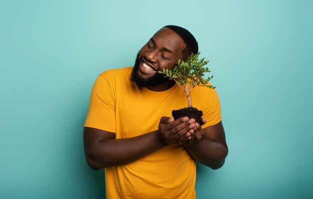 Heureux garçon noir aime un petit arbre prêt à être planté