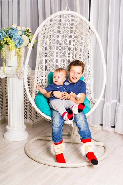 Heureux garçon et petit frère se détendre dans la salle blanche