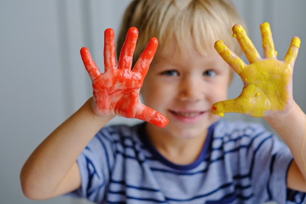 Heureux garçon de trois ans peignant des peintures au doigt