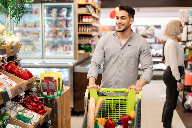 Heureux gars du Moyen-Orient faisant des courses dans un supermarché moderne