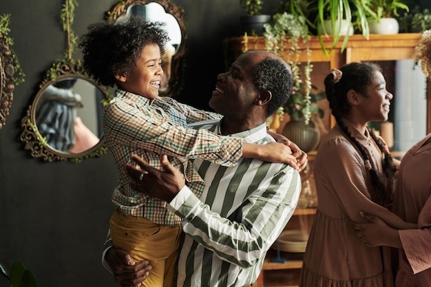 Heureux grand-père africain parlant à son petit-fils lors d'une fête à la maison en famille