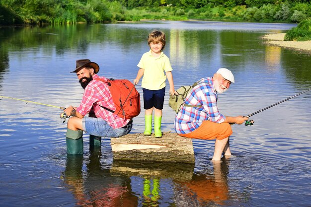 Heureux grand-père père et petit-fils avec des cannes à pêche sur la couchette de la rivière Homme enseignant aux enfants comment pêcher dans la rivière