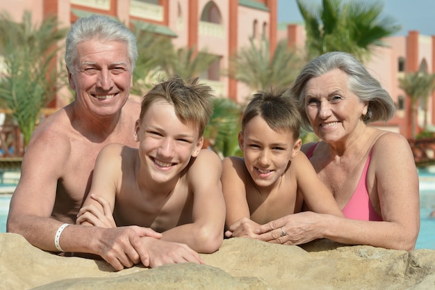 Heureux grands-parents avec leurs petits-enfants dans la piscine en vacances