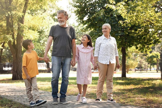 Heureux grands-parents avec de petits enfants marchant ensemble dans le parc