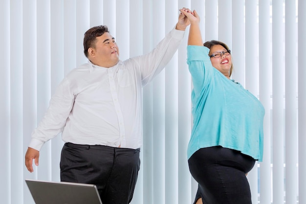 Heureux gros couple d'affaires dansant au bureau