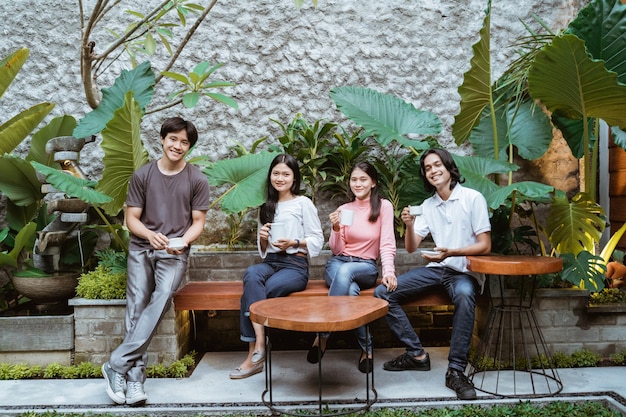 Heureux groupe d'amis souriant ayant une garden-party en plein air avec des boissons au café