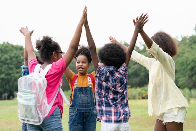 Heureux groupe amusant d'enfants afro-américains ont levé les mains ensemble en cercle dans le parc