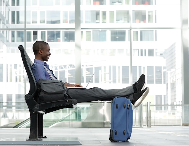 Heureux homme d&#39;affaires assis avec un ordinateur portable à la gare