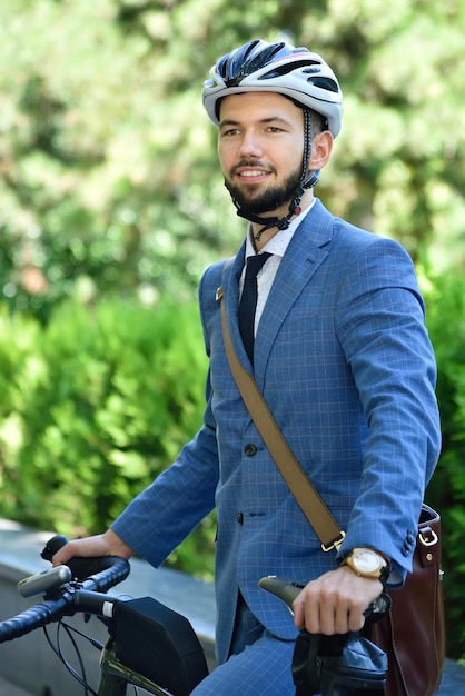 Heureux homme d'affaires barbu en casque avec vélo