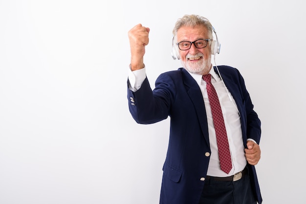 Heureux homme d'affaires barbu senior souriant tout en écoutant de la musique et à la recherche de motivation avec des lunettes sur blanc