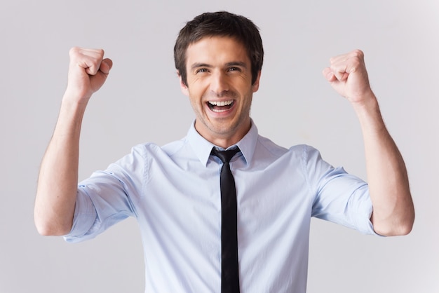 Heureux homme d'affaires. Beau jeune homme en chemise et cravate faisant des gestes et souriant