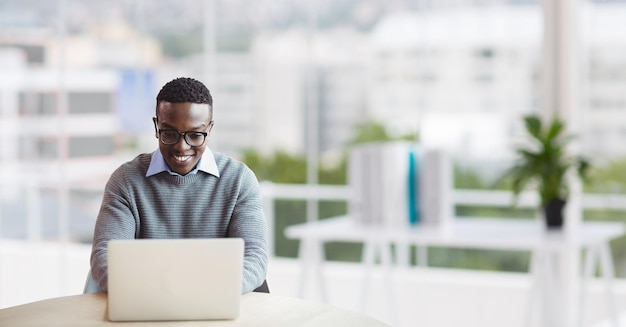 Heureux homme d'affaires à un bureau à l'aide d'un ordinateur