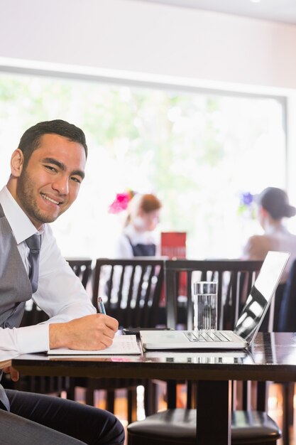 Heureux homme d&#39;affaires d&#39;écriture en souriant à la caméra