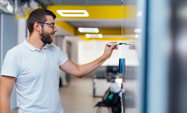 Heureux homme d'affaires écrivant quelque chose sur un tableau blanc au bureau